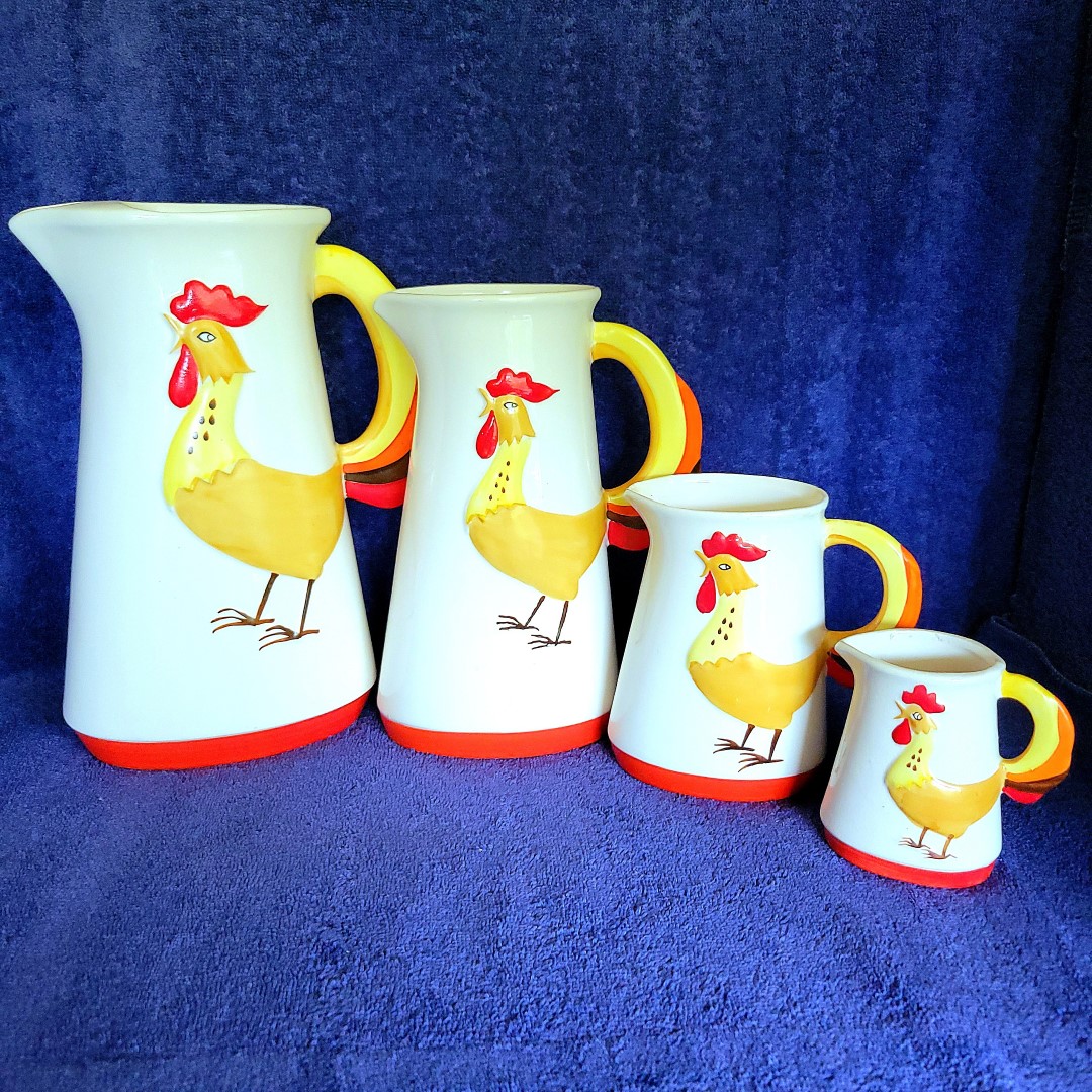 Four Holt Howard Coq Rouge pitchers arranged from largest to smallest.