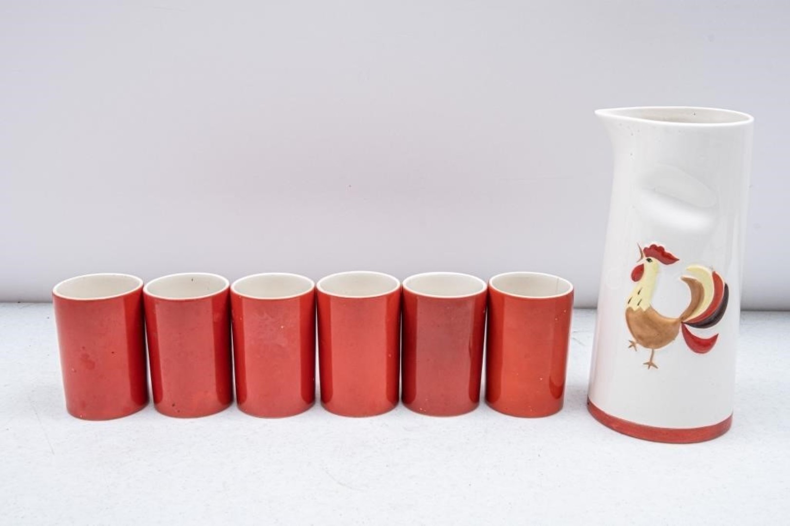 Holt Howard Coq Rouge handleless juice pitcher with six matching red-orange cups.