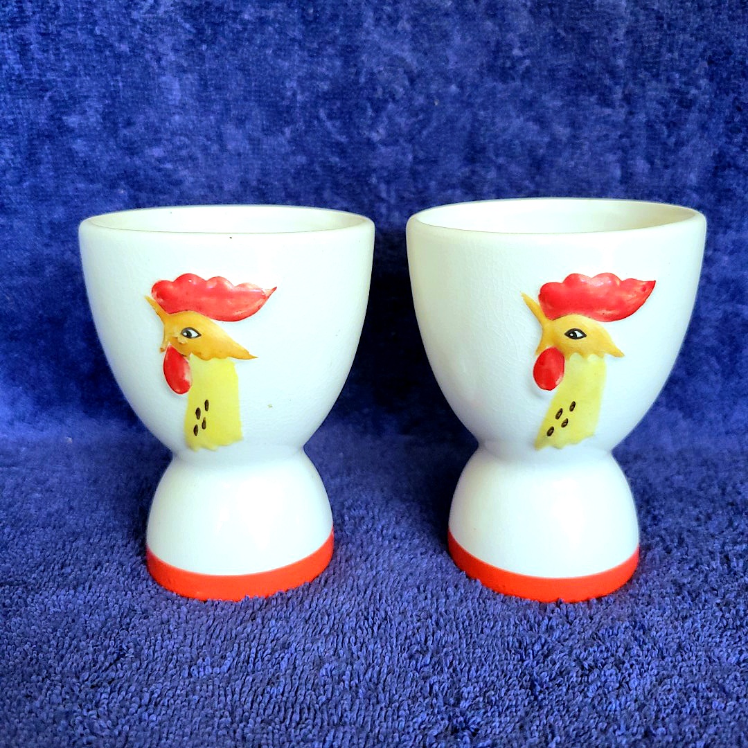 Two single-sided Holt Howard Coq Rouge egg cups showing the rooster-head decoration on the front.