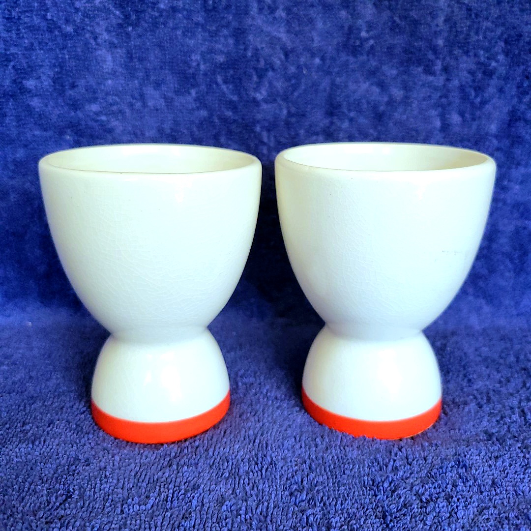 Reverse sides of two single-sided Holt Howard Coq Rouge egg cups showing no rooster decoration.