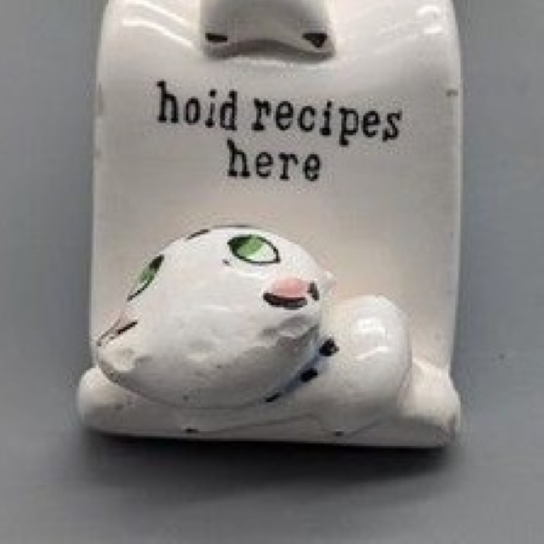 Detail of kitten at top of Cozy Kittens spoon rest beside words hold recipes here.