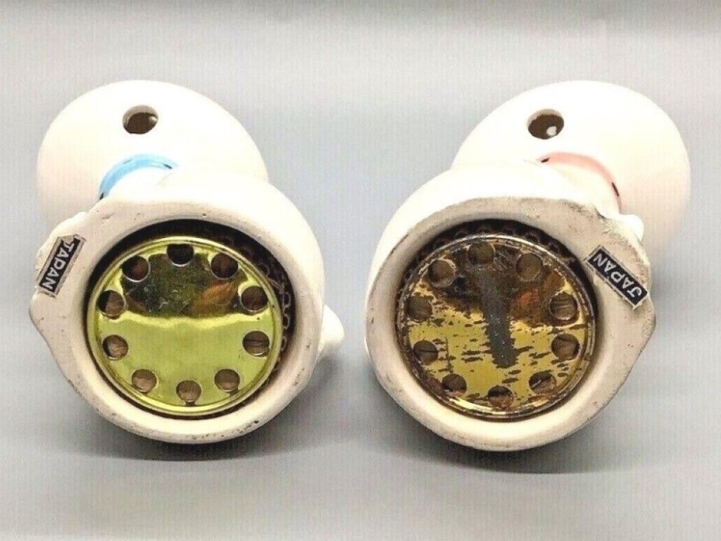 Undersides of Cozy Kittens tail-handle salt and pepper shakers showing metal mechanisms and Japan labels.